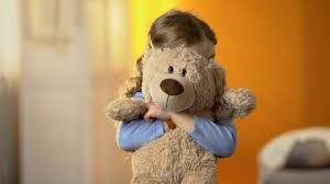 enfant serrant dans ses bras un ours en peluche